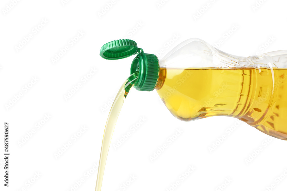 从白色背景上隔离的塑料瓶中倒入食用油。