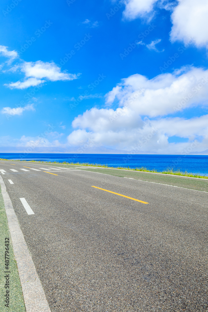 Empty asphalt highway and azure ocean nature scenery under blue sky