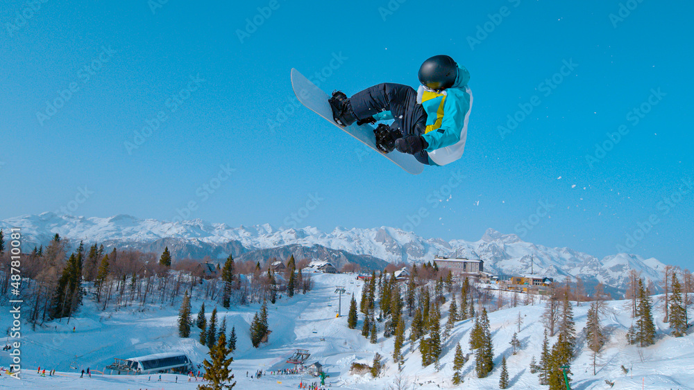 特写：滑雪板运动员在空中翱翔，并表演旋转抓握技巧。