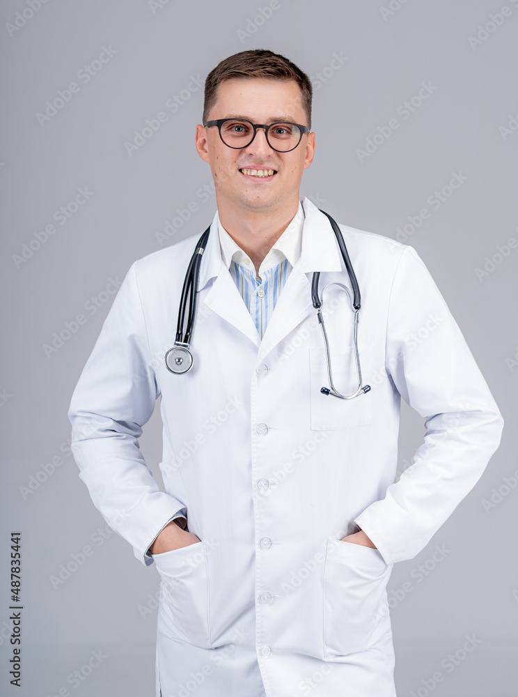 医生把手放在口袋里。医生戴着眼镜，背景是浅色的电话示波器。特写。
