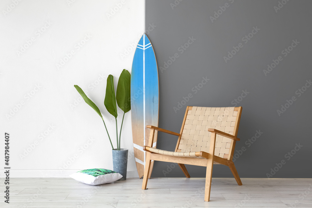 Surfboard, armchair and houseplant near wall