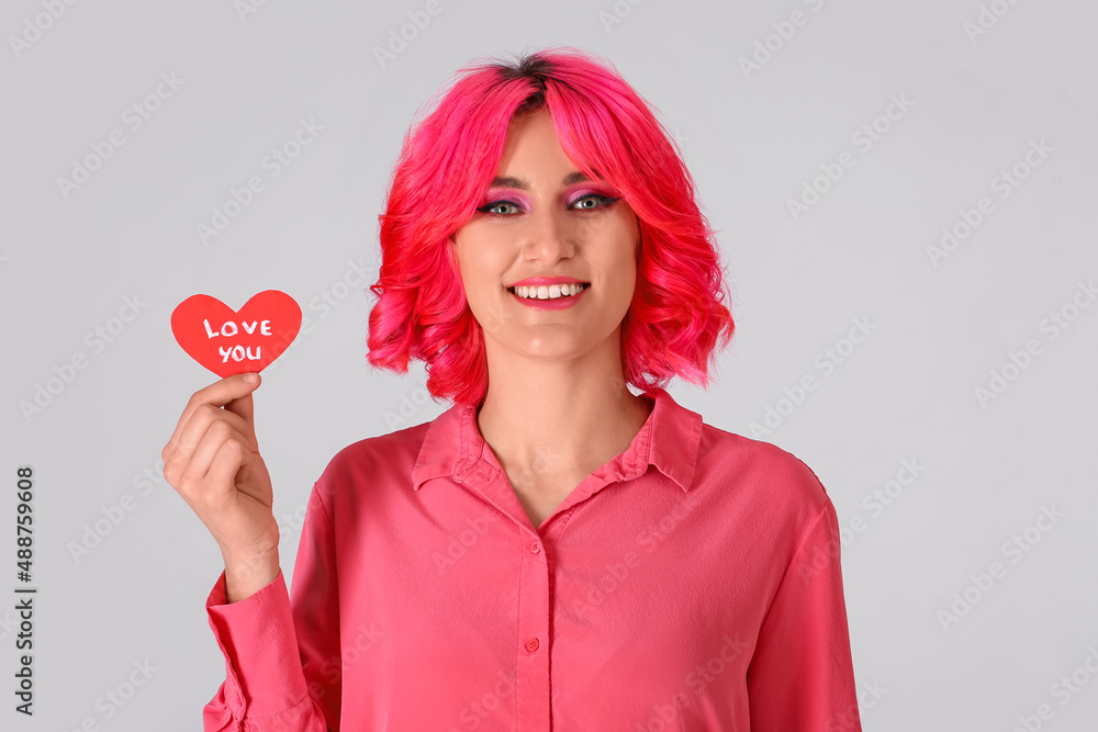 Stylish woman with bright hair and red heart on light background. Valentines Day celebration