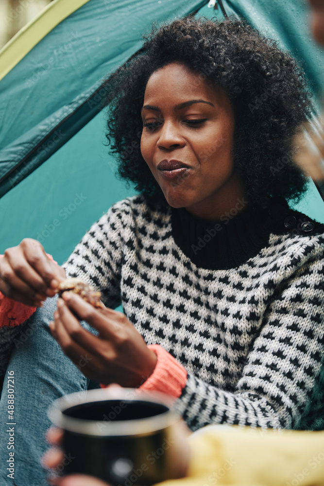 Smiling woman having a snack while camping