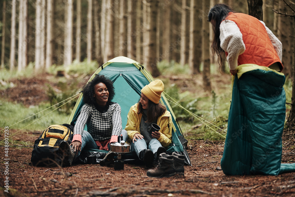 Friends laughing while camping in a forest