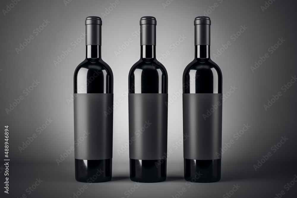Three black wine bottles with empty blank labels with copyspace for your brand on abstract dark back