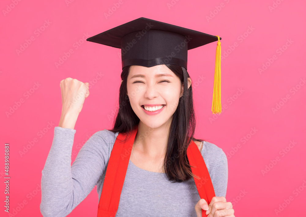 戴着毕业帽的快乐亚洲女大学生，带着成功的姿态