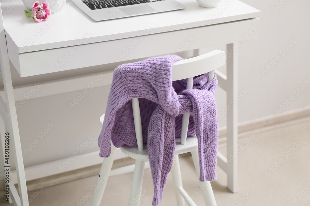 Knitted lilac sweater on chair in room