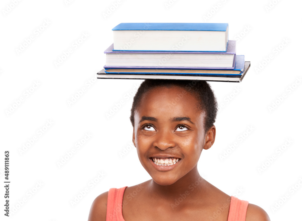 Perfecting my balance. Studio shot of a young african girl balancing books on her head isolated on w