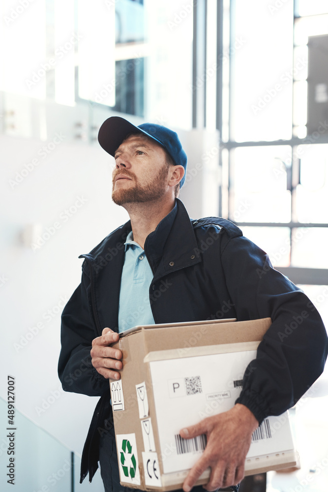 Hes on route to make a delivery. Shot of a handsome delivery man heading up a flight of stairs with 