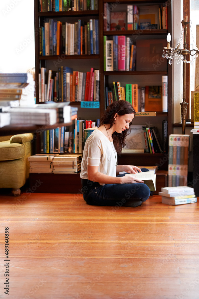 把她的阅读时间花进去。一个年轻女人盘腿坐在地板上阅读。