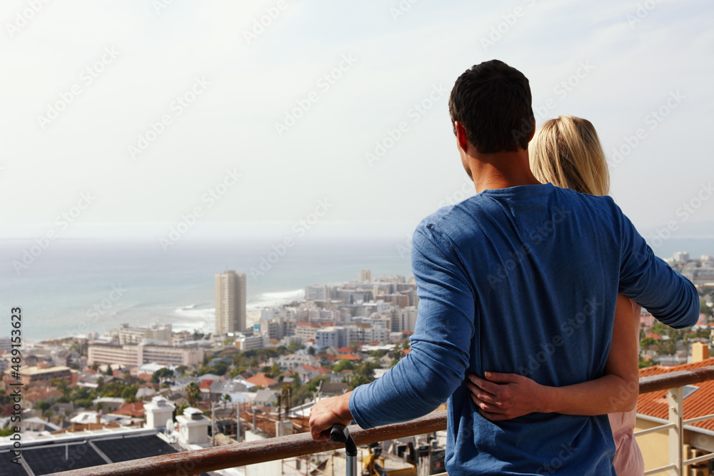 我们喜欢我们的新地方。一对幸福的夫妇站在阳台上俯瞰风景。