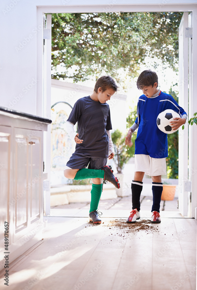 男孩就是男孩。两个男孩在足球练习后把泥土带进房子的镜头。