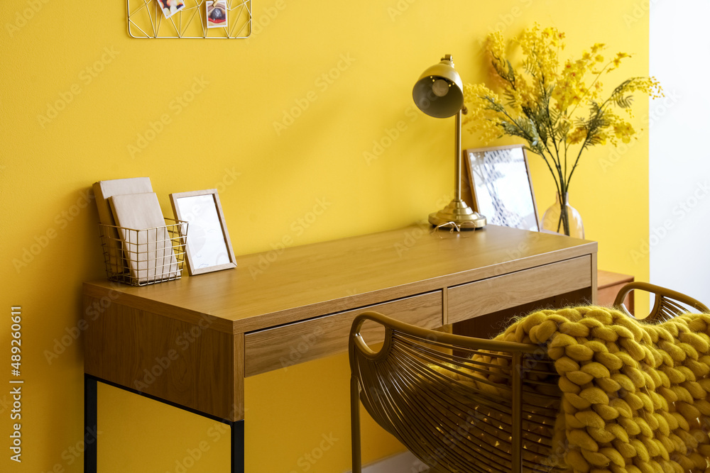 黄色墙壁附近有金色灯的木制桌子