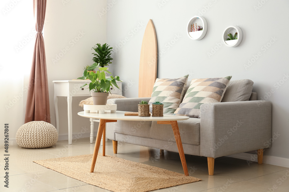 带木制冲浪板、桌子和沙发的浅色客厅内部
