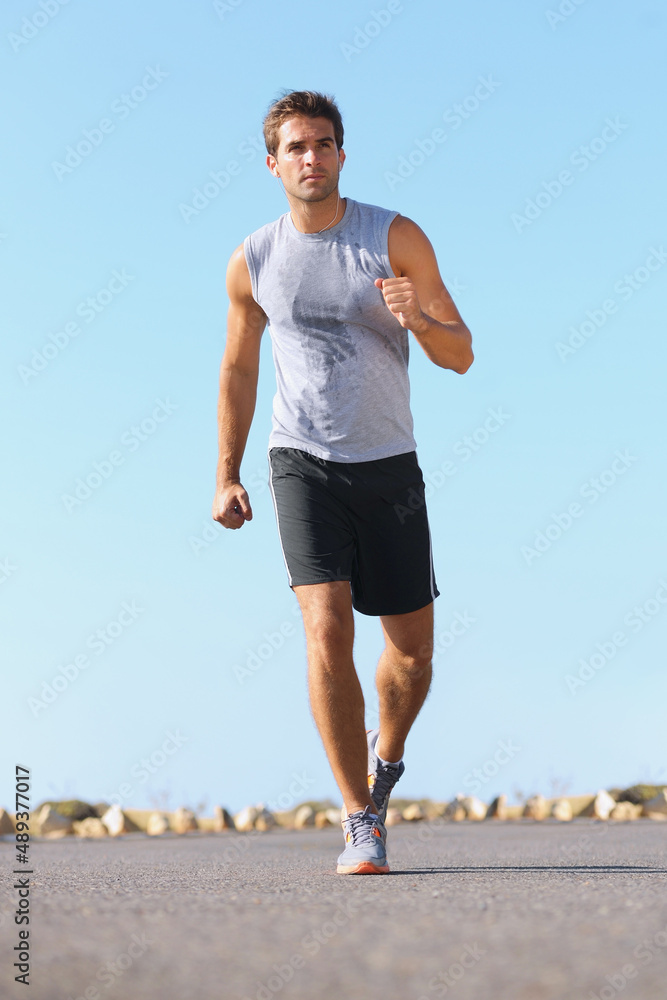 保持身体健康。英俊的年轻人在路上慢跑——全程。