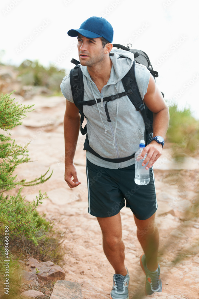 保持水分很重要。快乐的年轻徒步旅行者手里拿着一瓶水行走。