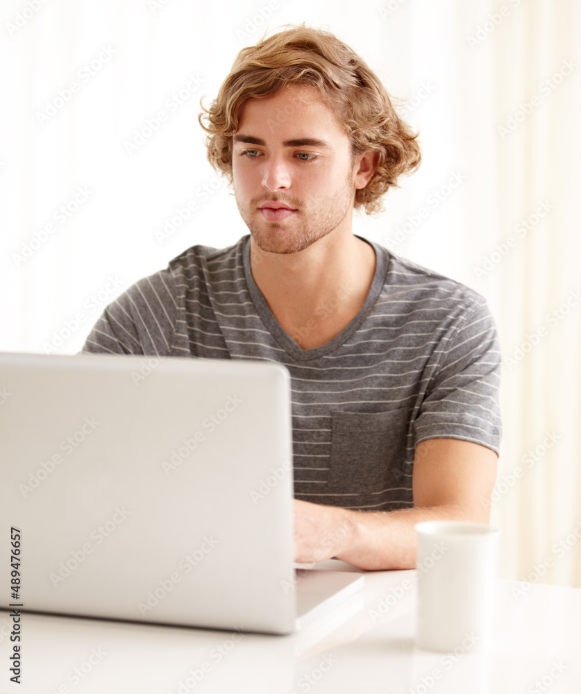 休息日喜欢上网。一个年轻人在家里用笔记本电脑。