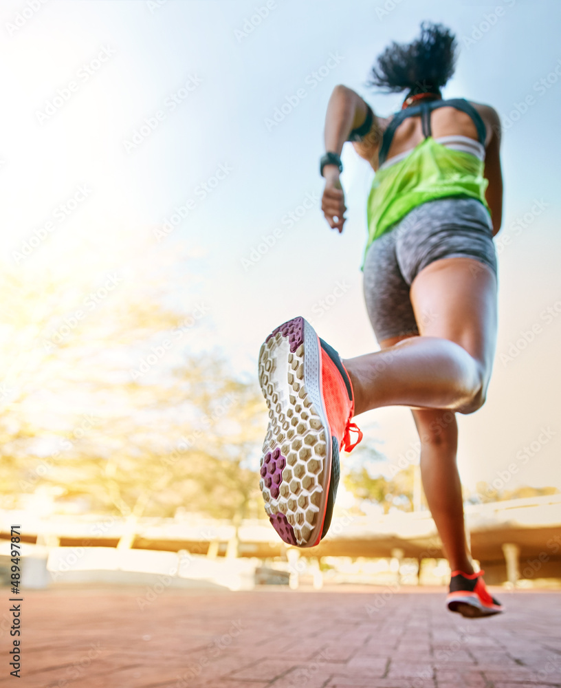 出发并征服你的目标。一位运动型年轻女子外出跑步的后视照片。