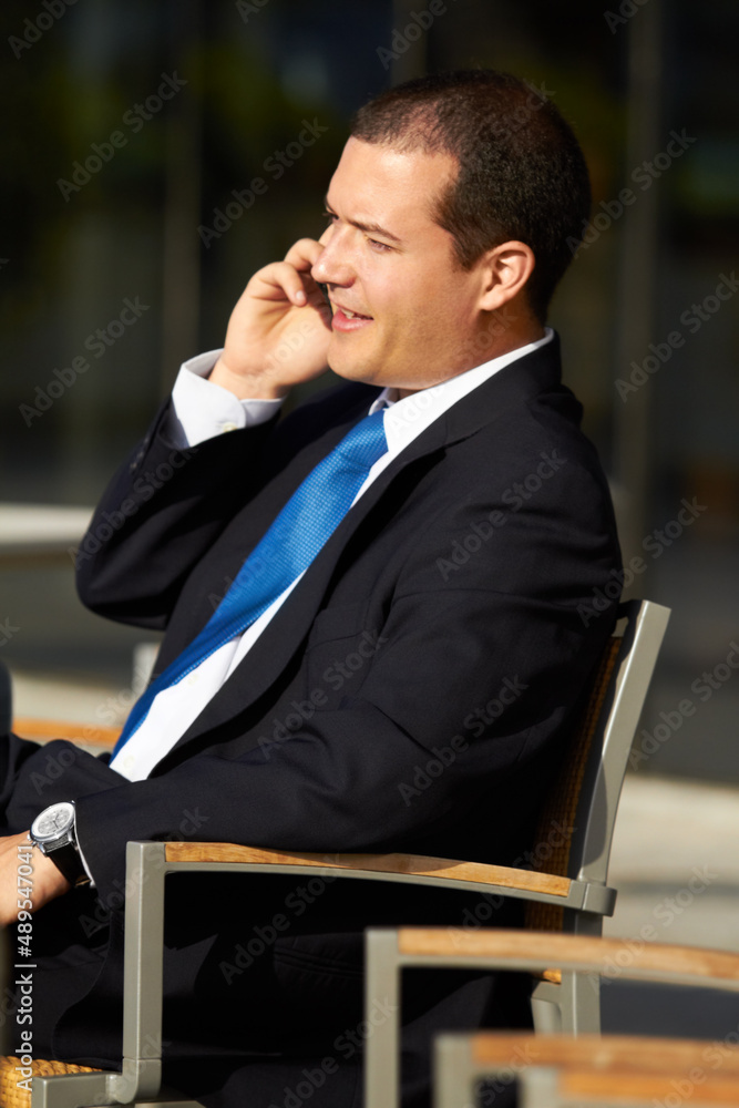 他从不太忙，不想给你打电话。一个商人坐在椅子上打手机。