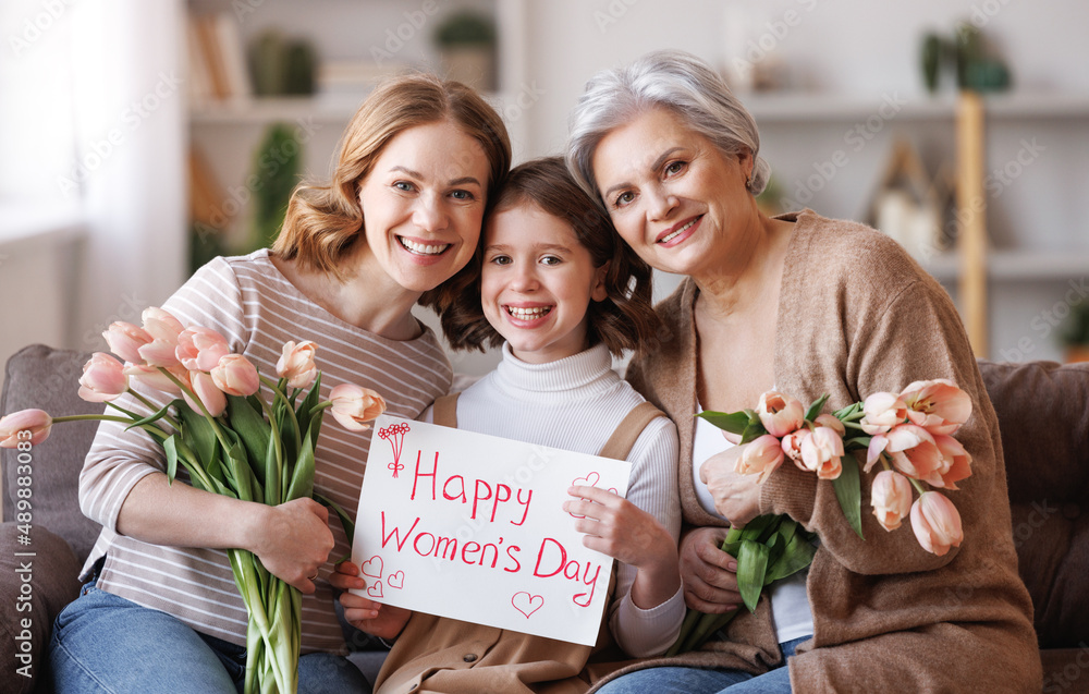 Happy International Womens Day! Smiling  family grandmother, mother and daughter with flowers and a