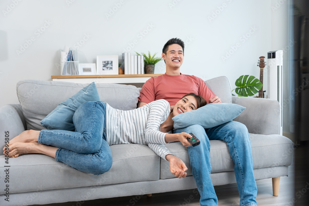 Asian young loving couple watch movie together in living room at home.