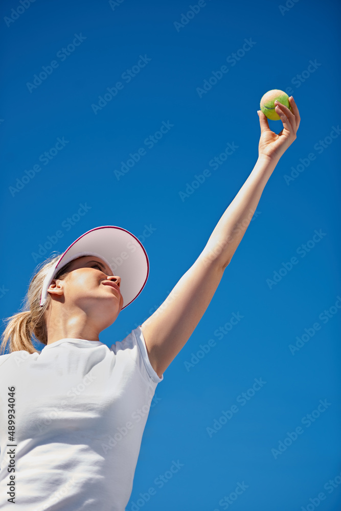 打她的对手。一名年轻的网球运动员在比赛中发球。