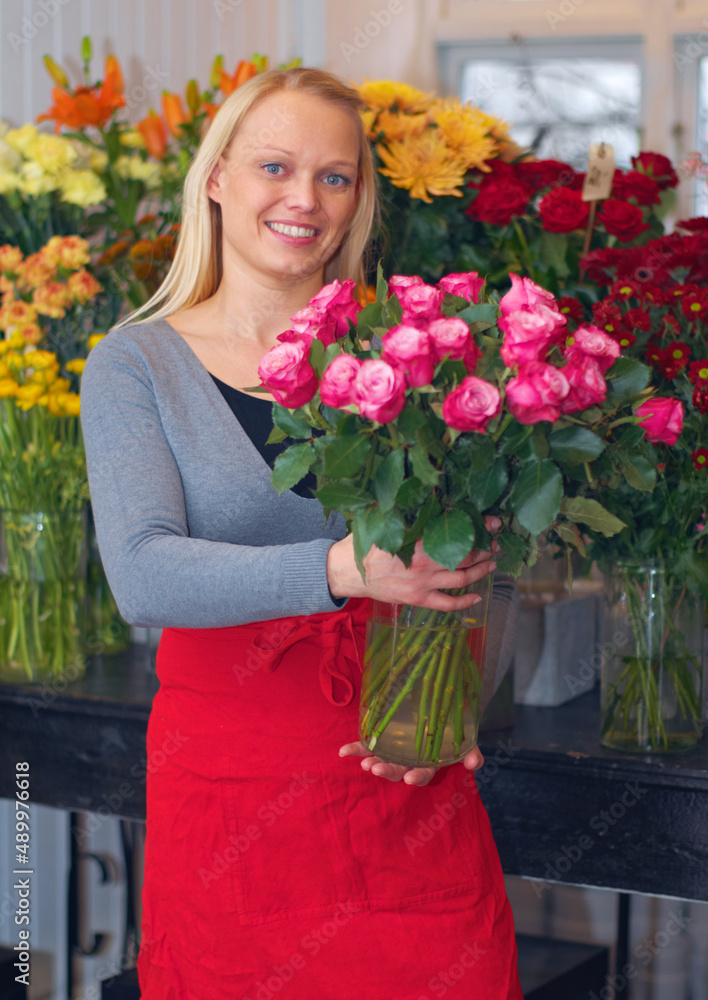 我是一位花艺大师。一张裁剪好的照片，一位女士拿着一束花站着。