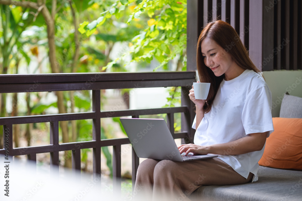 年轻女性在使用笔记本电脑工作或学习时喝咖啡的肖像