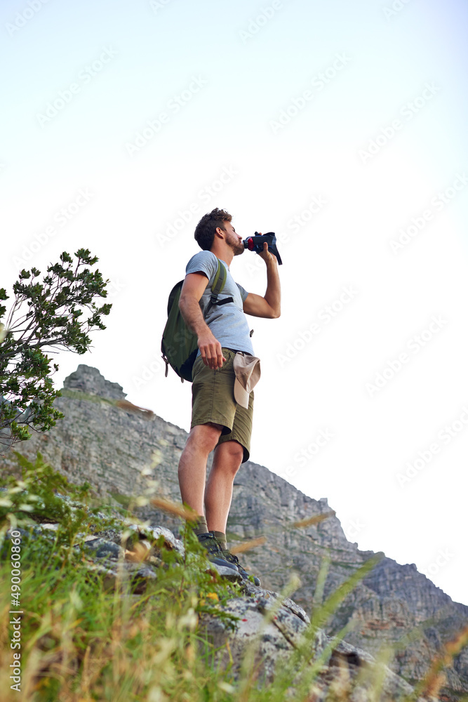 他永远不会忘记喝水。一个英俊的年轻人在徒步旅行时喝水的镜头。