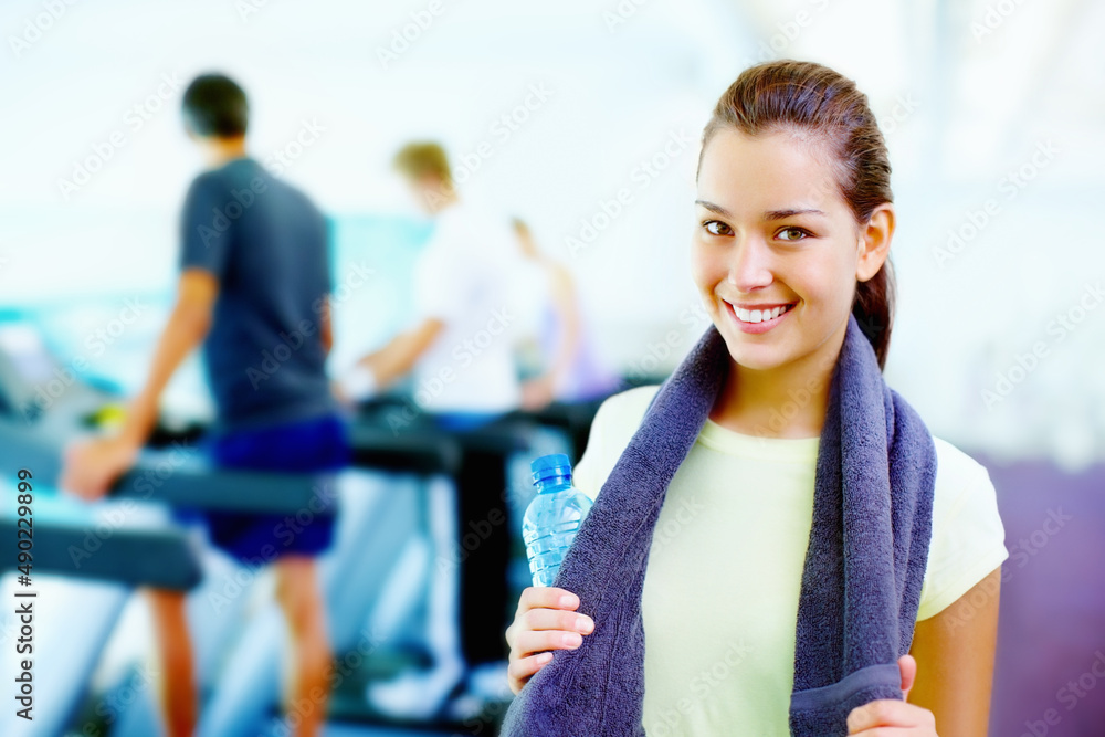 Young woman smiling. Portrait of young smiling woman holding water bottle and towel with people work