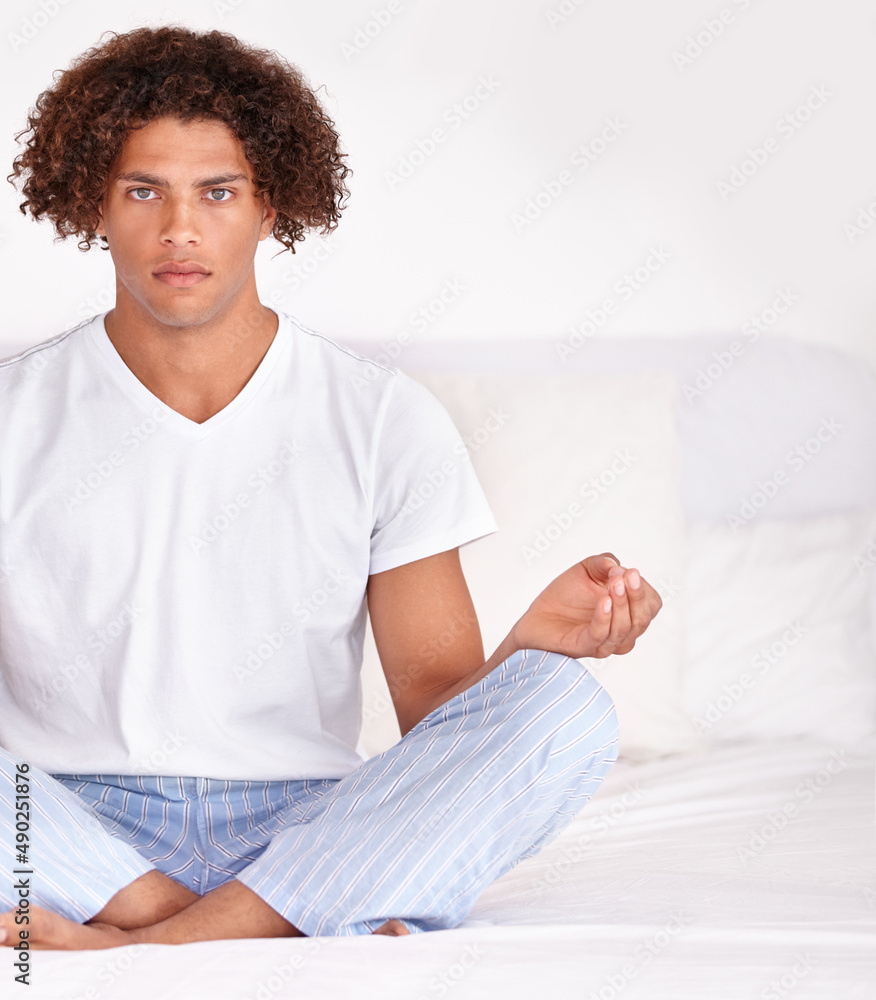 Finding his focus. Cropped portrait of a handsome young ethnic male sitting calmly on a bed and medi