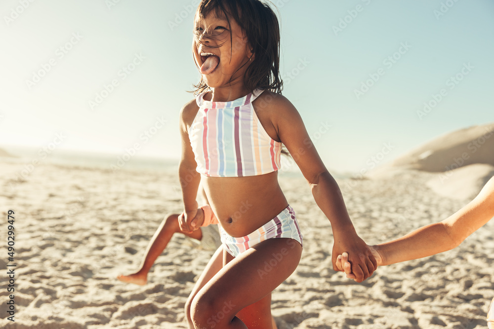 爱玩乐的小女孩和她的朋友在海滩上跑步