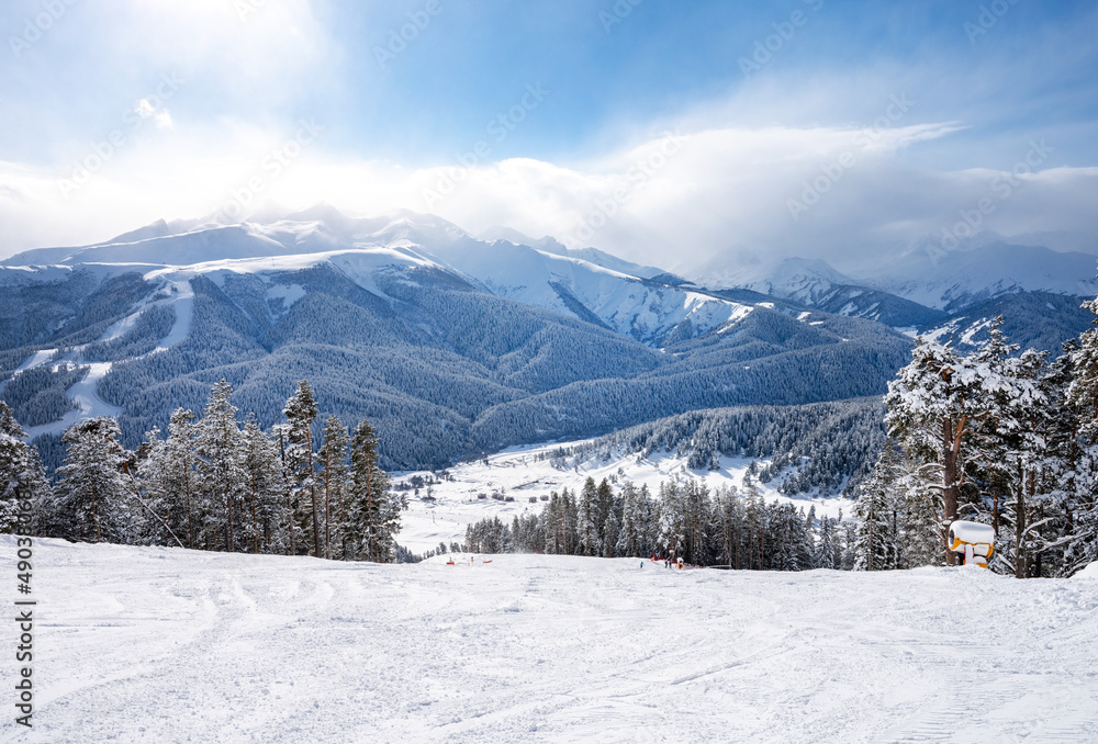 在阳光明媚的冬日里，Arkhyz滑雪场的美丽风景，有山、雪、森林和赛道