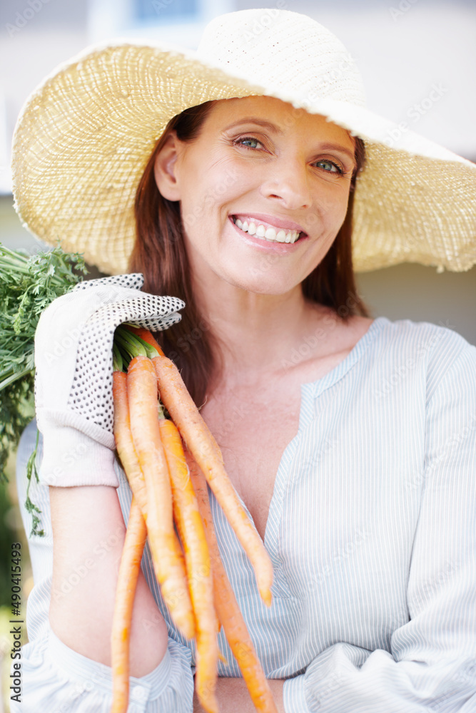 A bunch of goodness. Portrait of a smiling woman holding up a bunch of carrots.