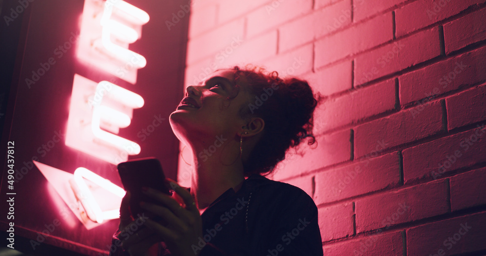 这里的联系很好。一名年轻女子站在大楼外使用手机的照片