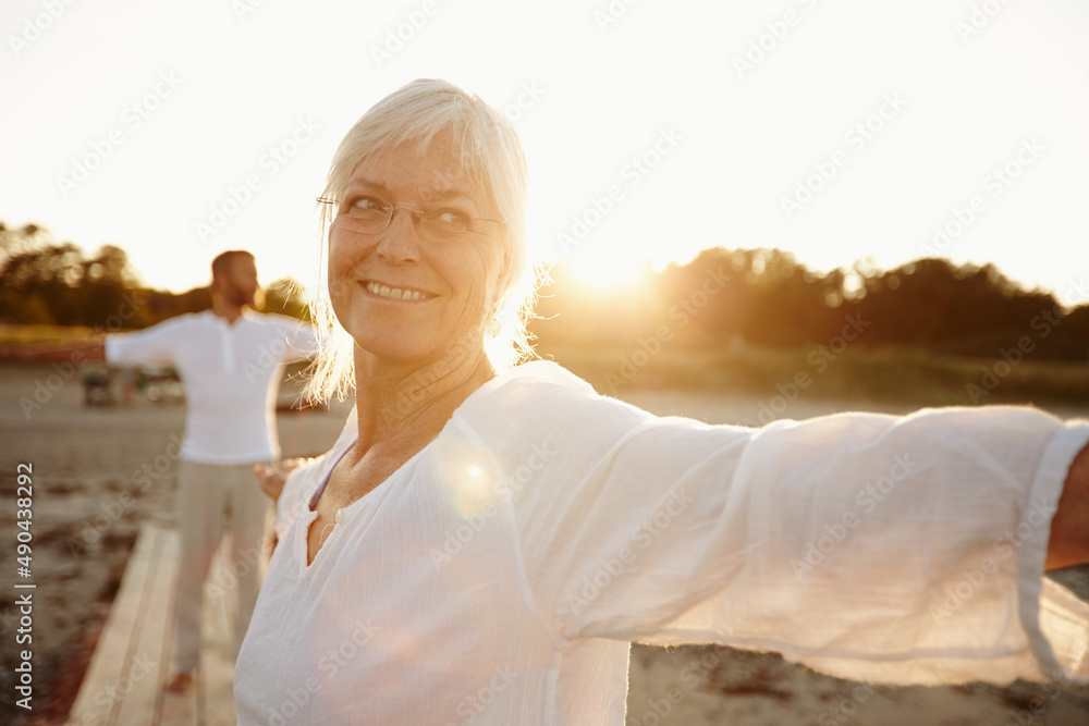 每一天都是瑜伽日。一个成熟的女人和她的丈夫在海滩上做瑜伽的镜头
