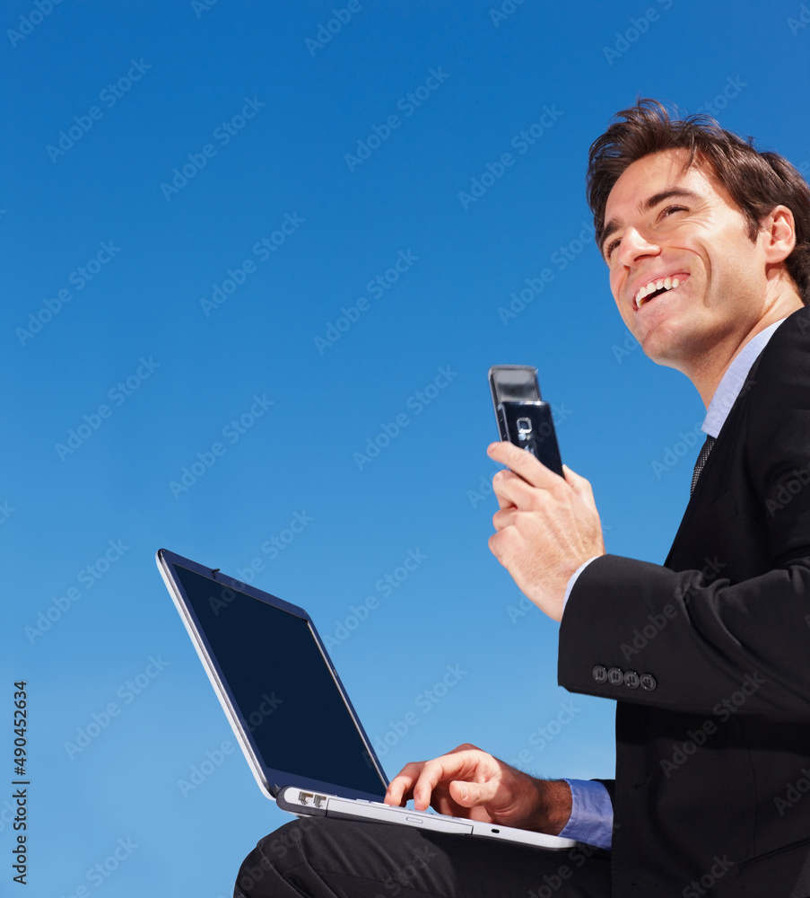 business man using a laptop while holding a mobile phone. Successful young business man using a lapt