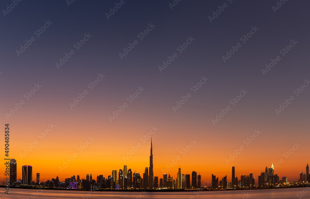日落后迪拜商业湾与哈利法塔的天际线，橙色和紫色的天空，高分辨率