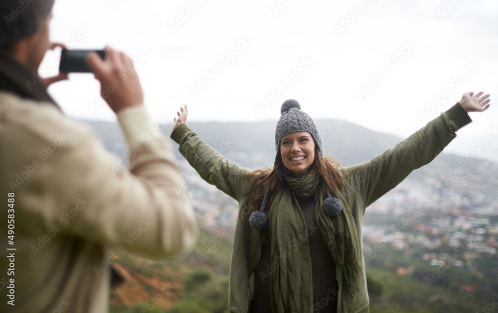 一定要欣赏风景。一对年轻夫妇在山上徒步旅行时拍照。