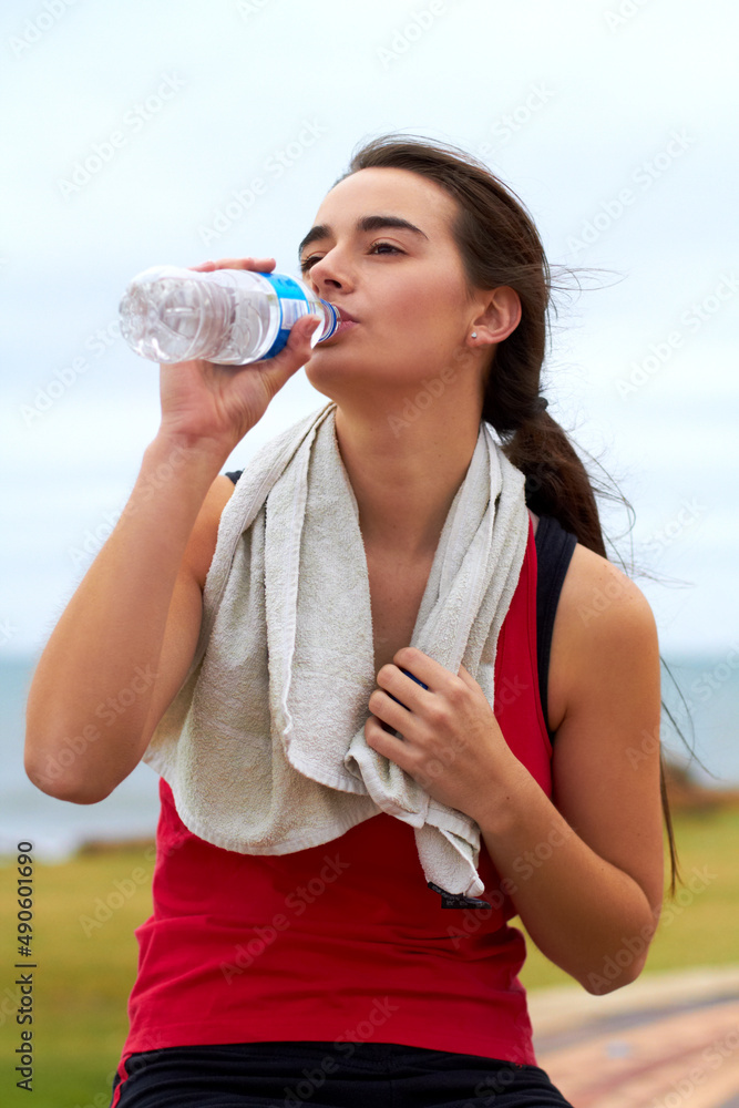 Glug glug. A young woman drinking water after her workout.