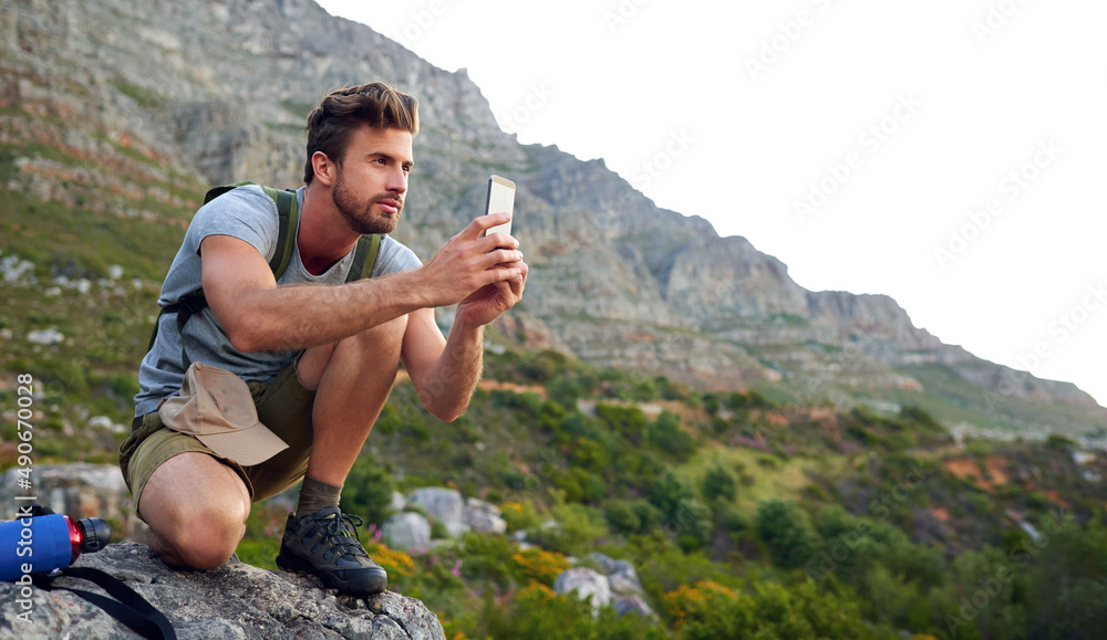 Ive gotta get some pics. Shot of a handsome young man snapping pics while hiking.