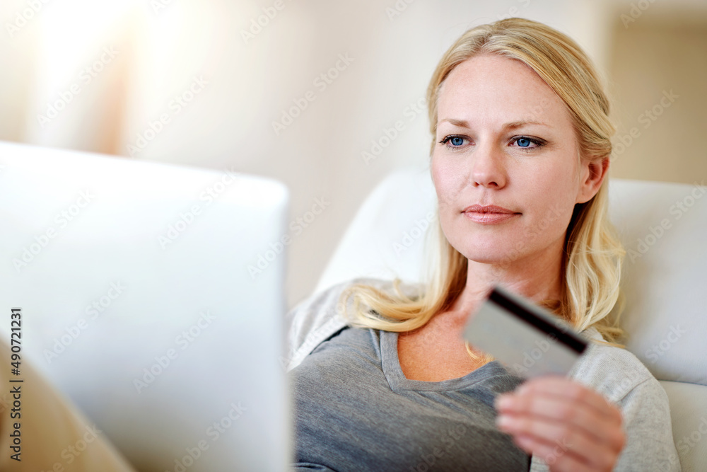 点击购买。一个女人在家里的沙发上网上购物的镜头。