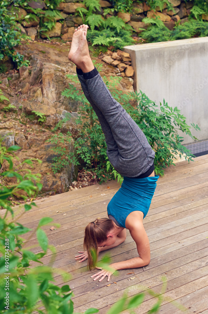 力量和平衡保持一致。一名年轻女子在户外练习瑜伽的照片。