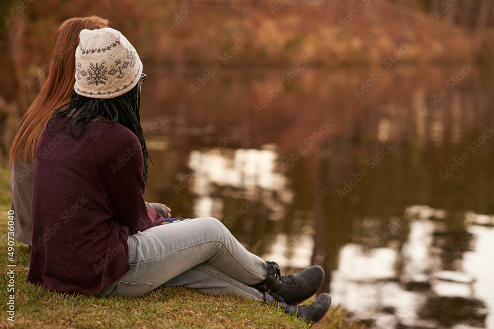 湖边一个美丽的冬日。两个十几岁的女孩在傍晚坐在湖边的照片