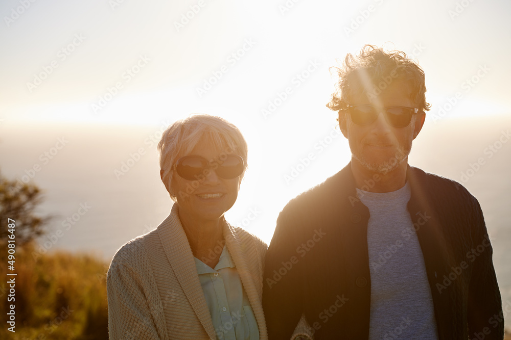 欣赏日落。一对老年夫妇一起站在山坡上的裁剪图。
