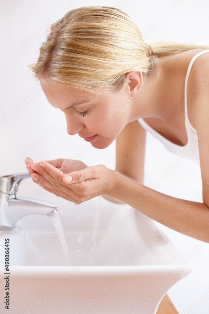 保持健康美丽的皮肤。一位有魅力的年轻女子用水洗脸的照片