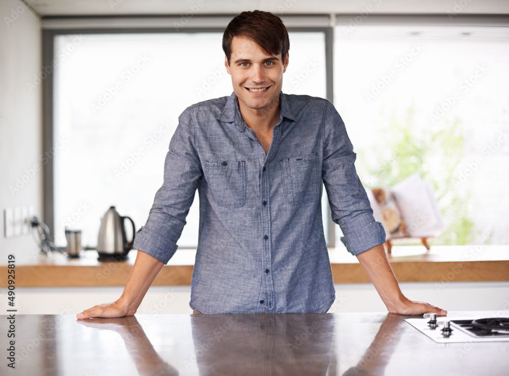 没有什么地方比得上家。一个英俊的年轻人站在厨房台面后面的肖像