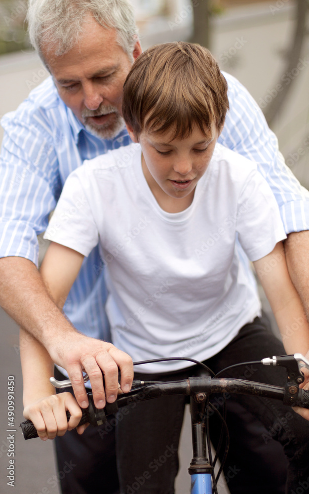 回到自行车上。小男孩在父亲的帮助下学习如何骑自行车。