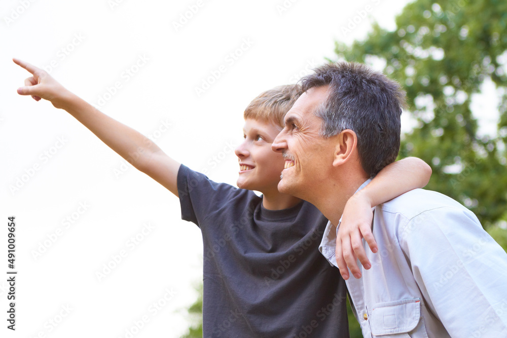What type of bird is that, dad. Young boy hold his arm around his fathers neck while pointing up int