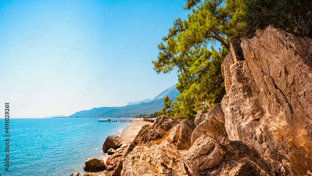 美丽的地中海海滩自然透视图，岩石、绿色雪松、平静的绿松石